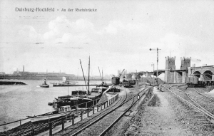 Kultushafen mit erste Eisenbahnbrücke nach Rheinhausen. Auf der anderen Rheinseite erkennt man die Krupp'schen Hüttenwerke. Die Eisenbahntrassen im Vordergrund gibt es zum Teil immer noch.